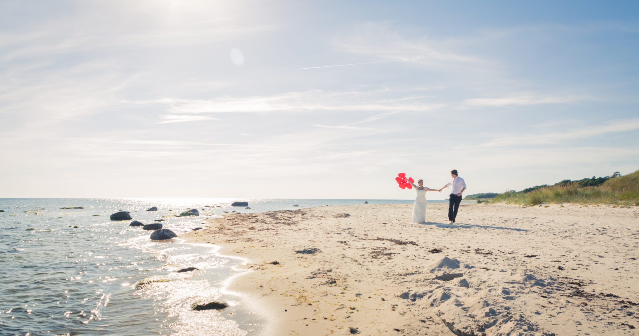 Brautpaar mit Luftballons in der Natur am Strand