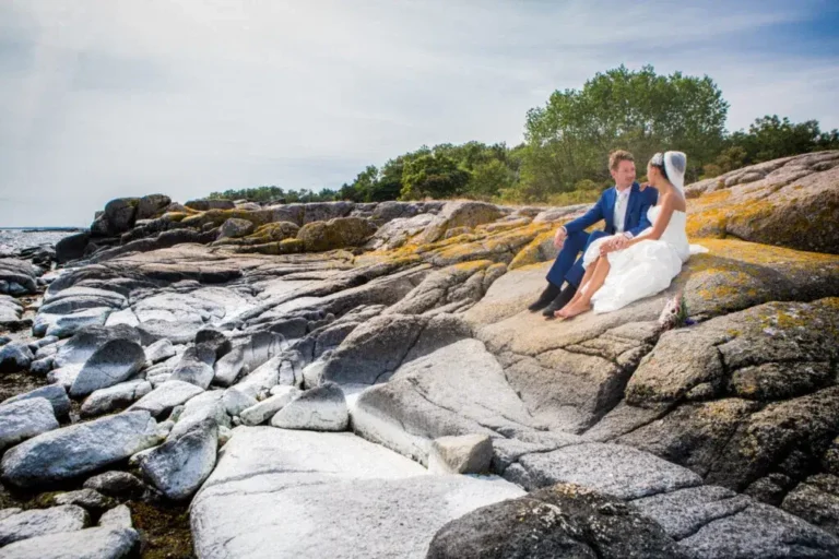 Bride and Groom sitting on the rocks on a beach on the Danish island of Bornholm on their wedding day