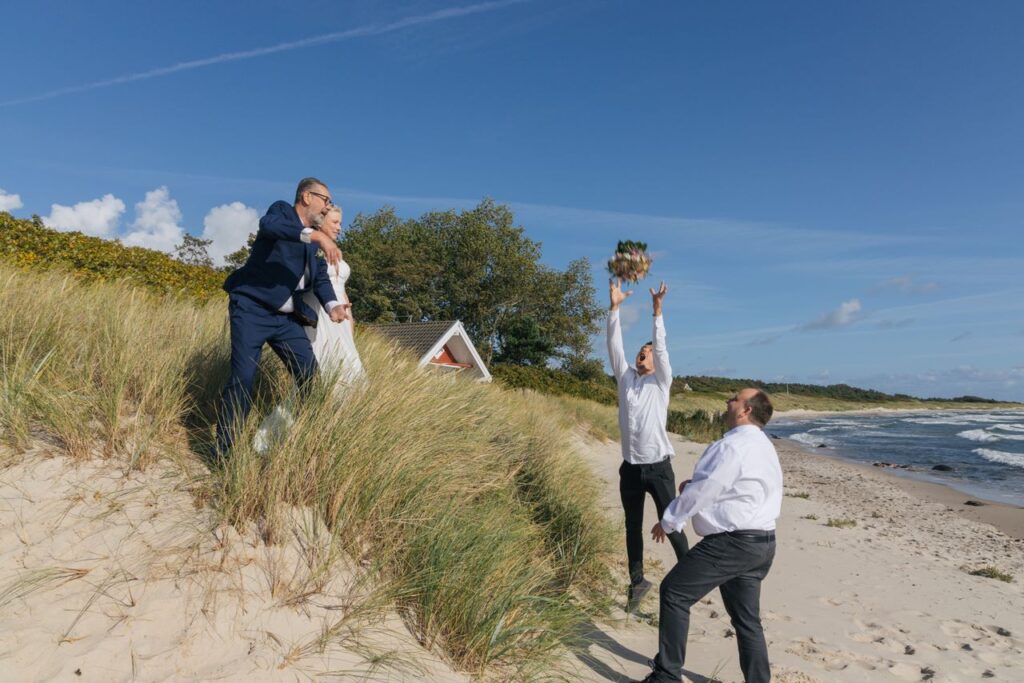 A groom on the Danish island of Bornholm tosses the bridal bouquet to the best man