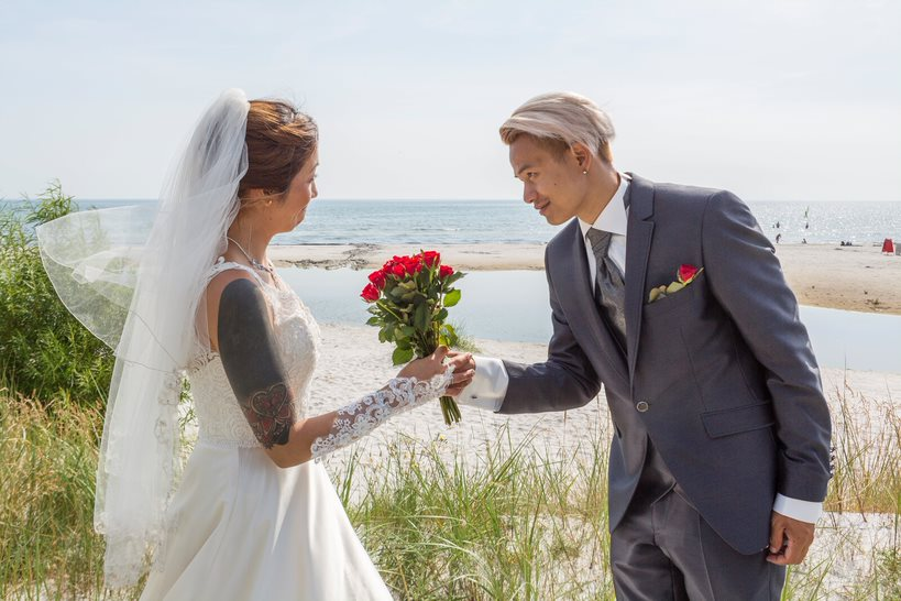 A groom gives his bride the wedding bouquet on Balka Beach on Bornholm.