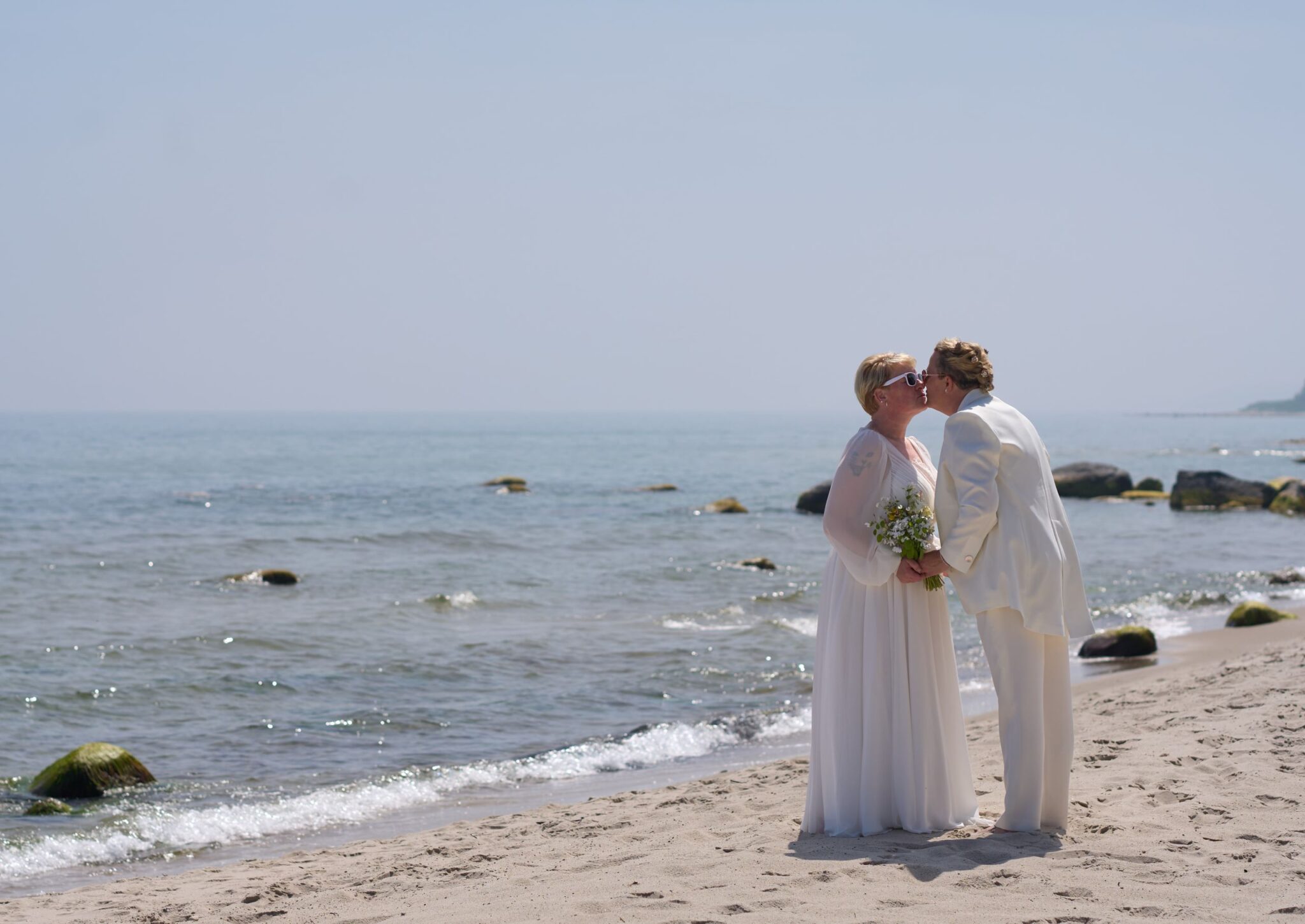 Ein lesbisches Paar am Strand von Bornholm kurz nach ihrer Hochzeit in Dänemark.