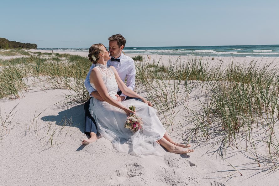 Braut und Bräutigam nach einer Strandhochzeit auf dem weißen Sand eines Strandes auf Bornholm in Dänemark.