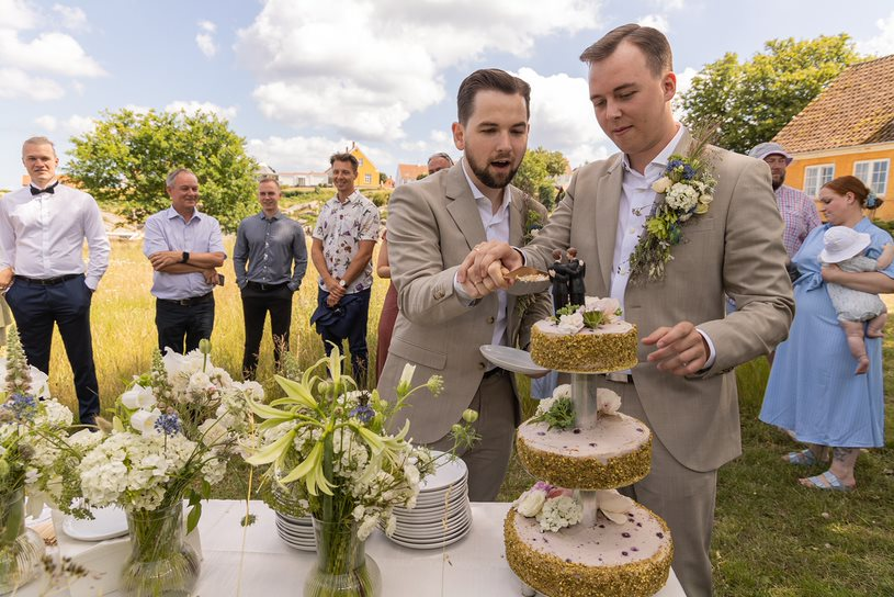 Schwules Hochzeitspaar schneidet die Hochzeitstorte an auf Bornholm