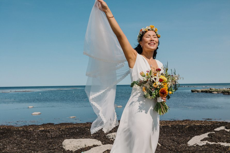 A bride on the beach on Bornholm blinks against the light.