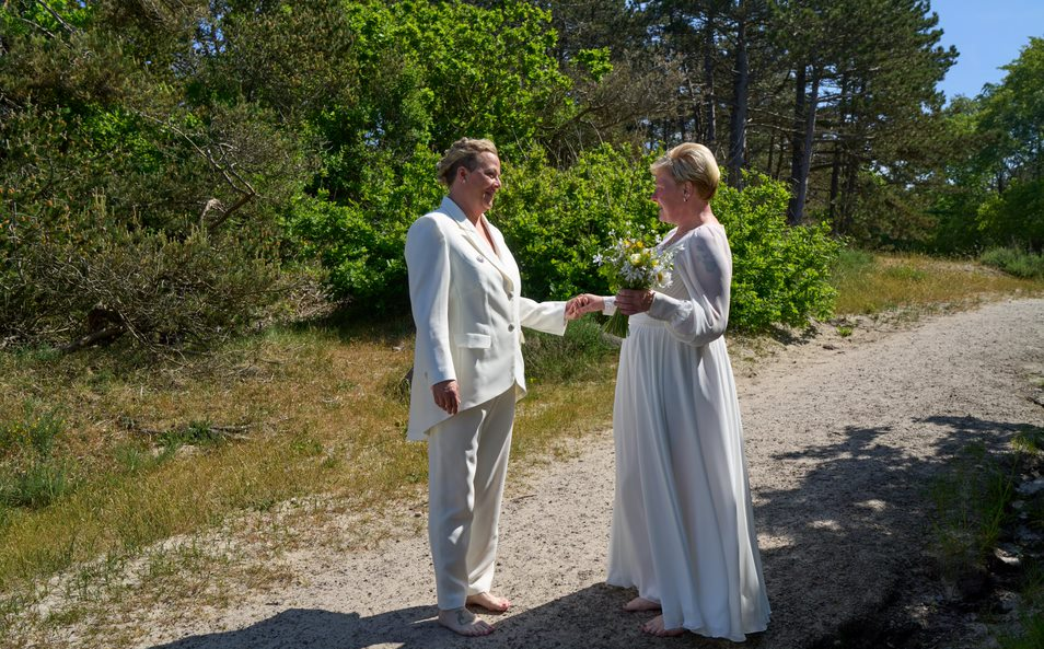 A same sex female couple to be married walks down the wedding aisle in nature on Bornholm in Denmark.