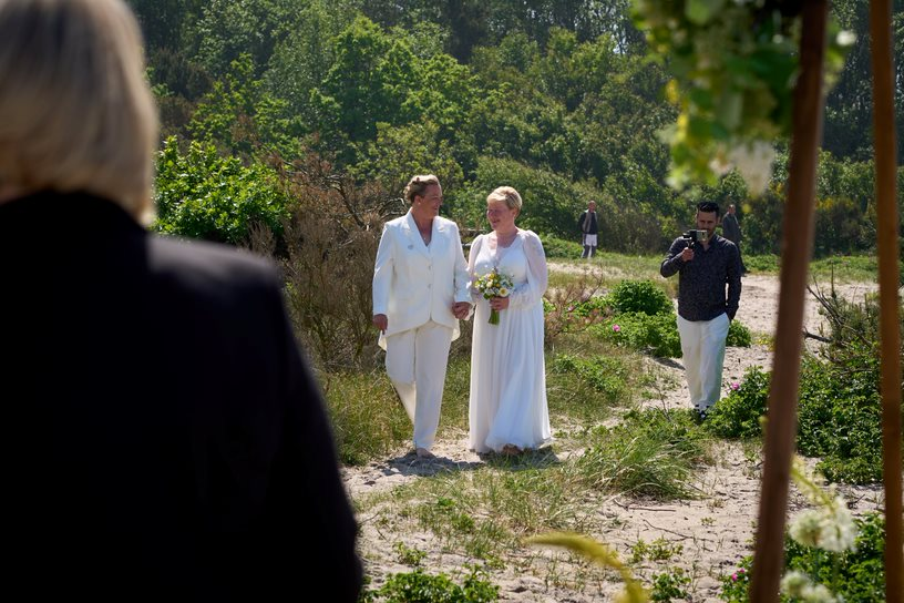 A lesbian couple walks down the aisle in nature to their beach wedding held on the island of Bornholm.