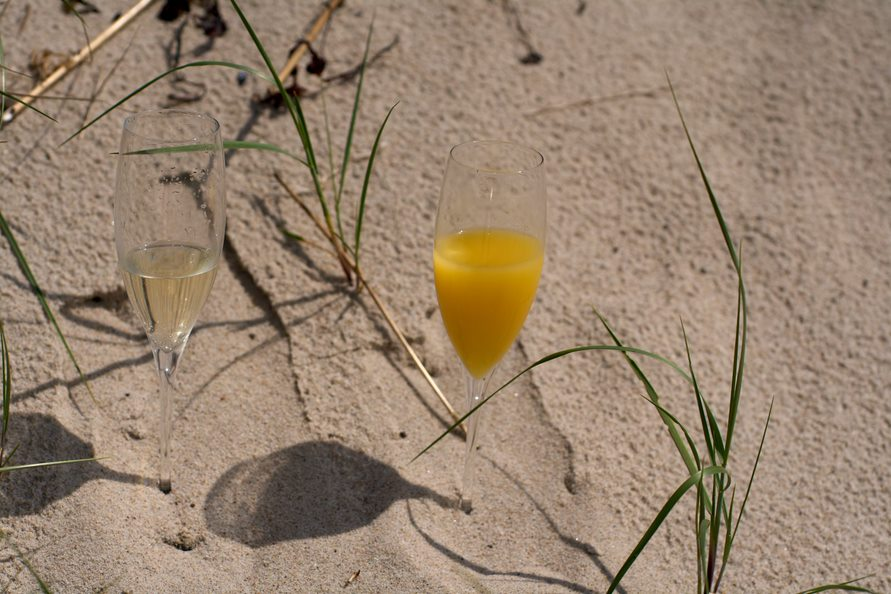 Sektgläser im Sand während einer Strandhochzeit auf der Insel Bornholm in Dänemark.