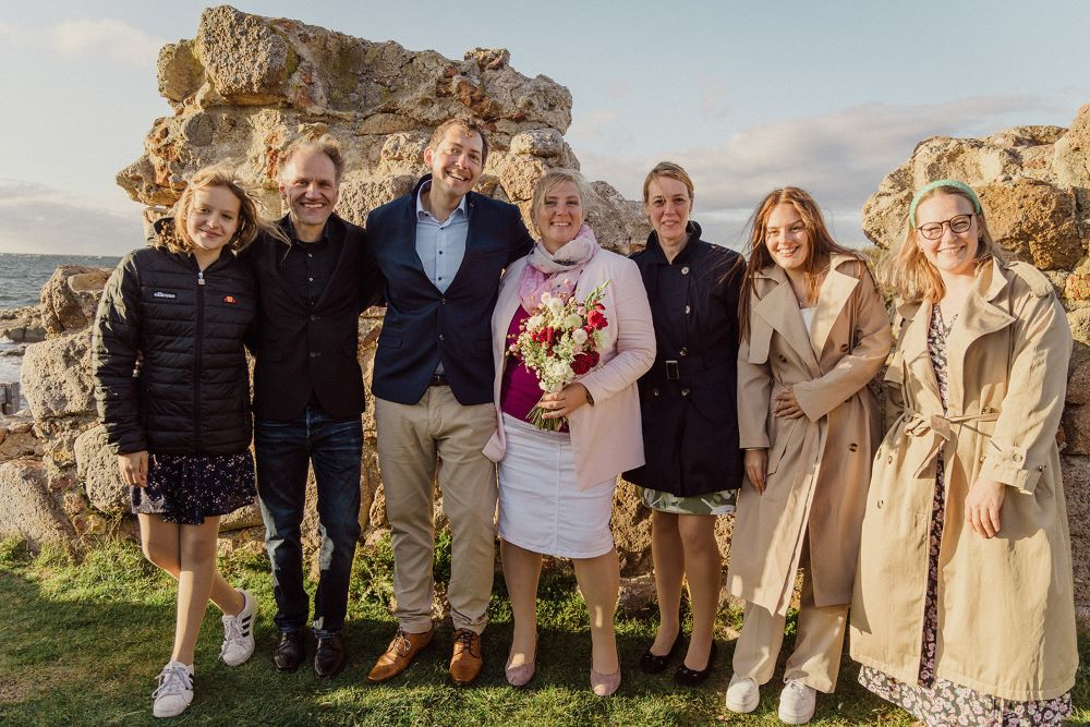 Ein frisch verheiratetes deutsches Paar mit seinen Hochzeitsgästen und dem Standesbeamten, der die Trauung auf Bornholm vollzog.