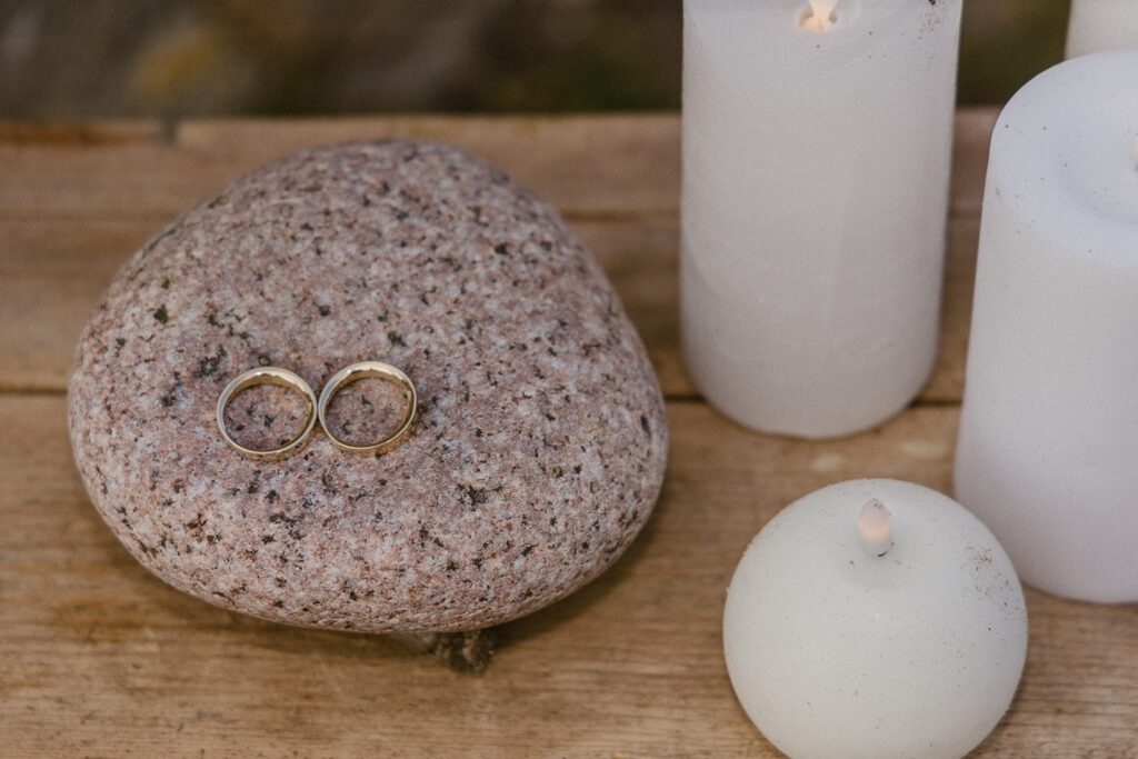 Eheringe auf einem Stein und Kerzenlichtdekoration für eine Hochzeit an einem historischen Ort auf der dänischen Insel Bornholm.