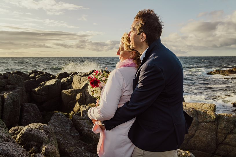 Ein frisch verheiratetes Paar blickt auf das wilde Meer im Norden von Bornholm in Dänemark.