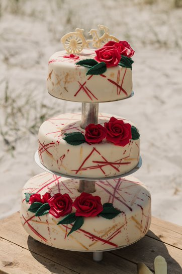 Tiered wedding cake with floral decorations on the beach in Denmark.
