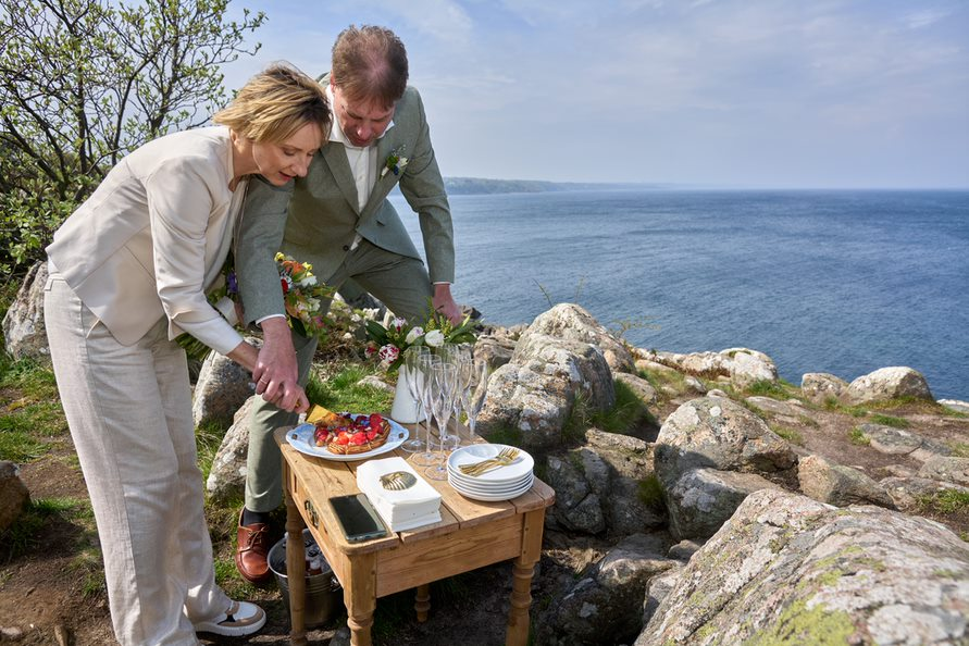 A German newly-wedded couple cuts the wedding cake on a clifftop on Bornholm in Denmark.