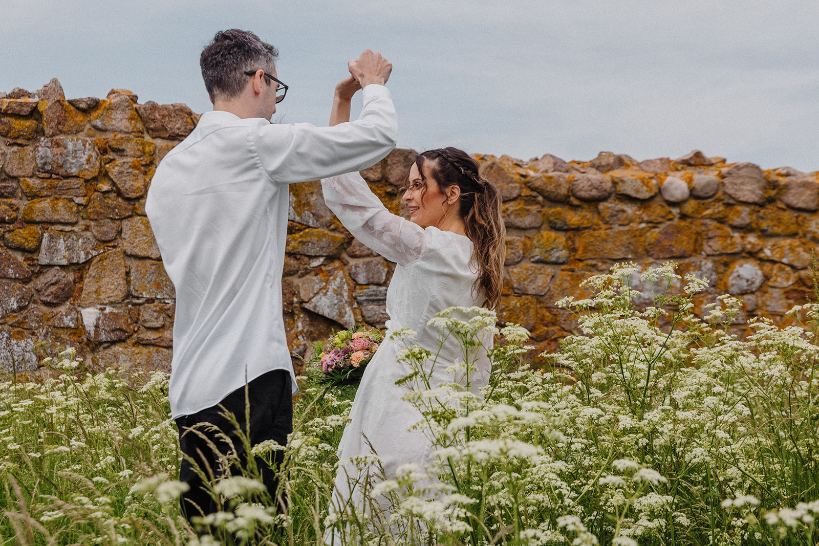 Bride and groom dance in front of the historic walls of Hammerhus castle on Bornholm in Denmark.