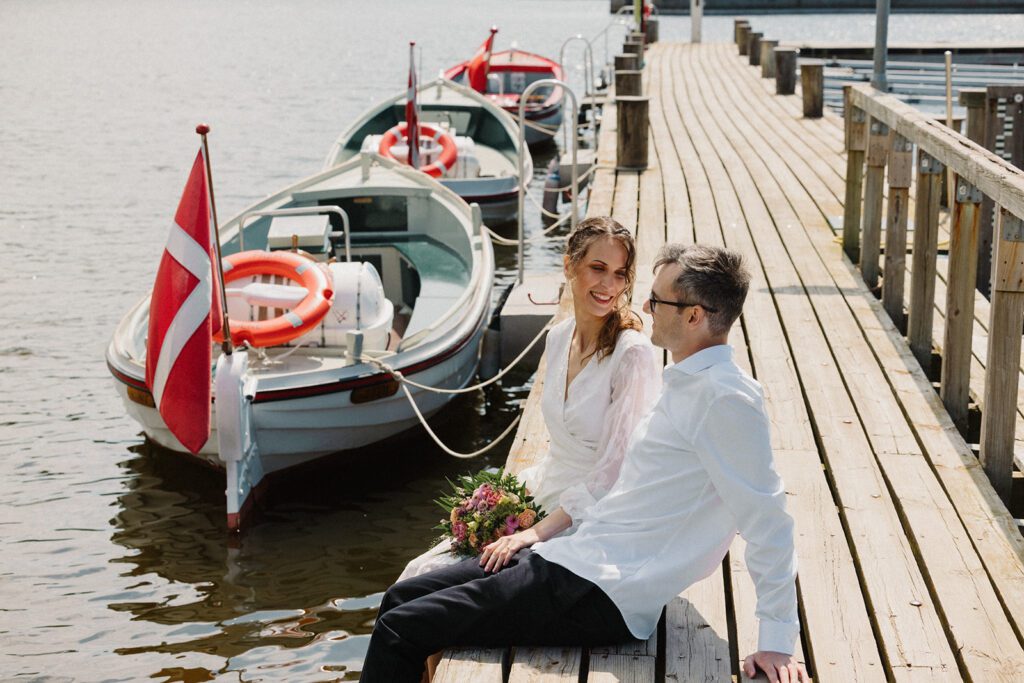 A just married couple are sitting in Hammershus Harbour on Bornholm for the photo shoot of their wedding.