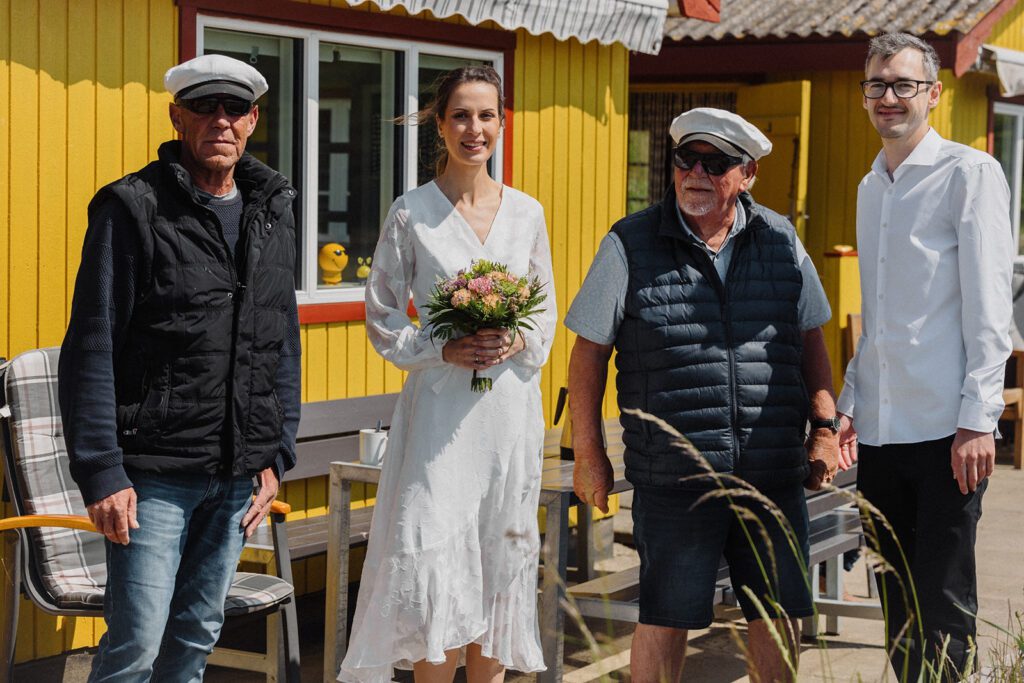 Bride and groom after a wedding on Bornholm in Denmark pose with a sea captain for the wedding photo.