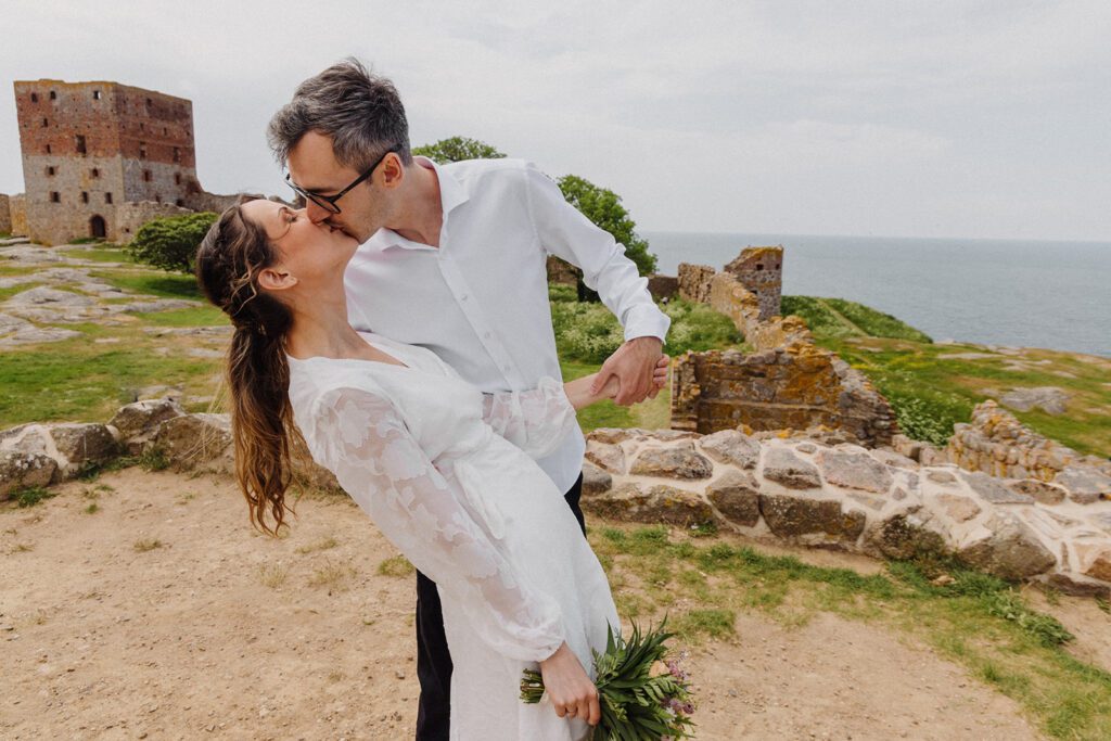 A couple kisses after their wedding on the historic site of Hammerhus on Bornholm.