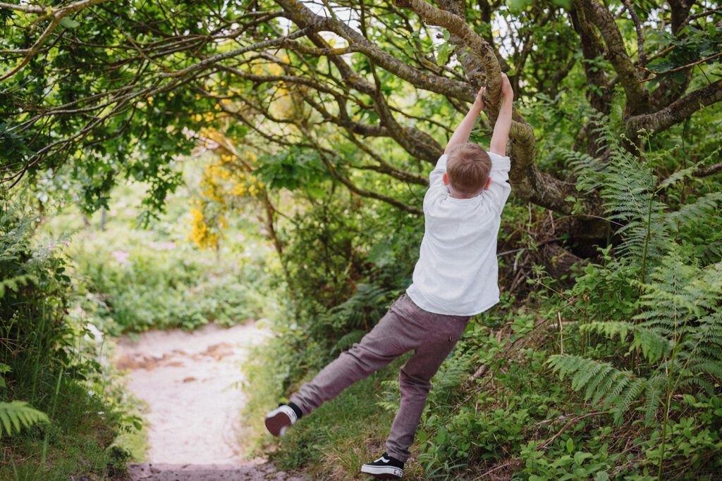 A boy swings on a tree branch after the wedding of his parents on Bornholm.