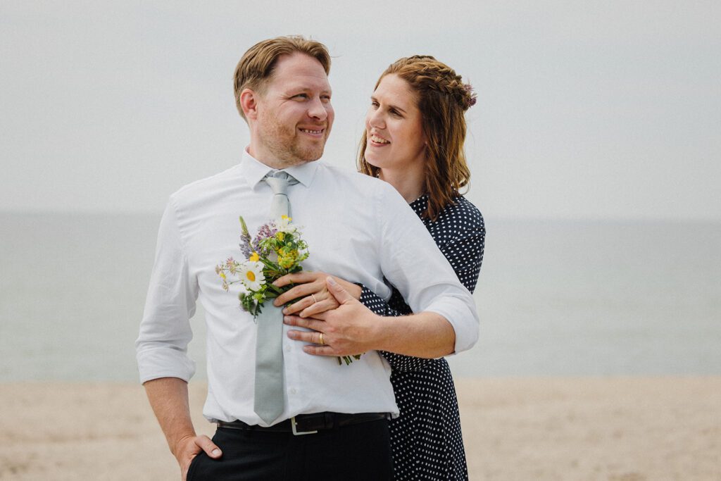 Bride and groom look lovingly at each other on a Danish beach after their wedding ceremony.