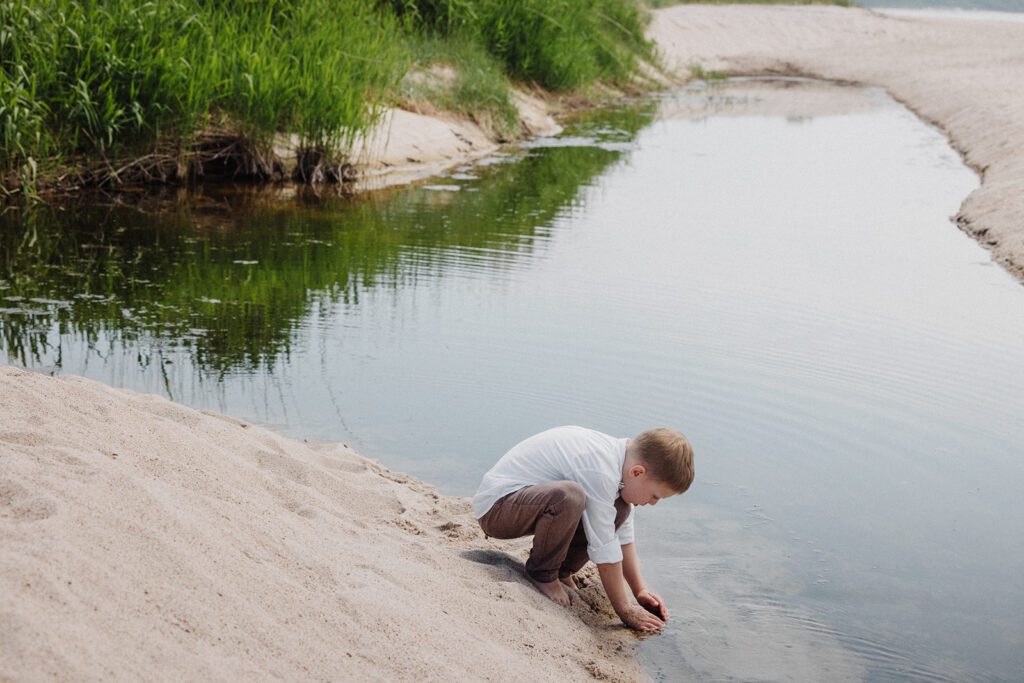 A boy plays at a rockpool on a beach in Bornholm after the wedding of his parents.