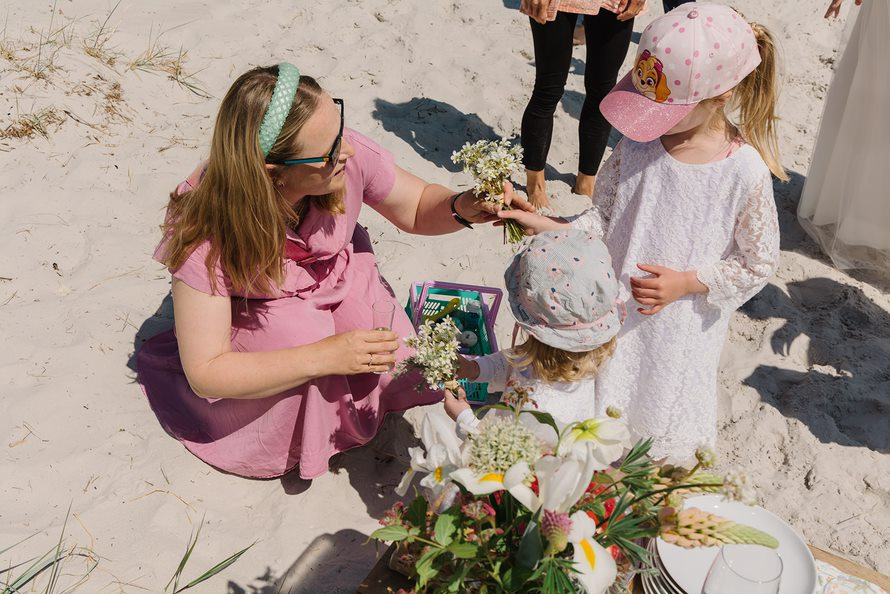 Eine dänische Hochzeitsplanerin auf Bornholm hilft Kindern bei einer Hochzeit mit dem Blumenschmuck.