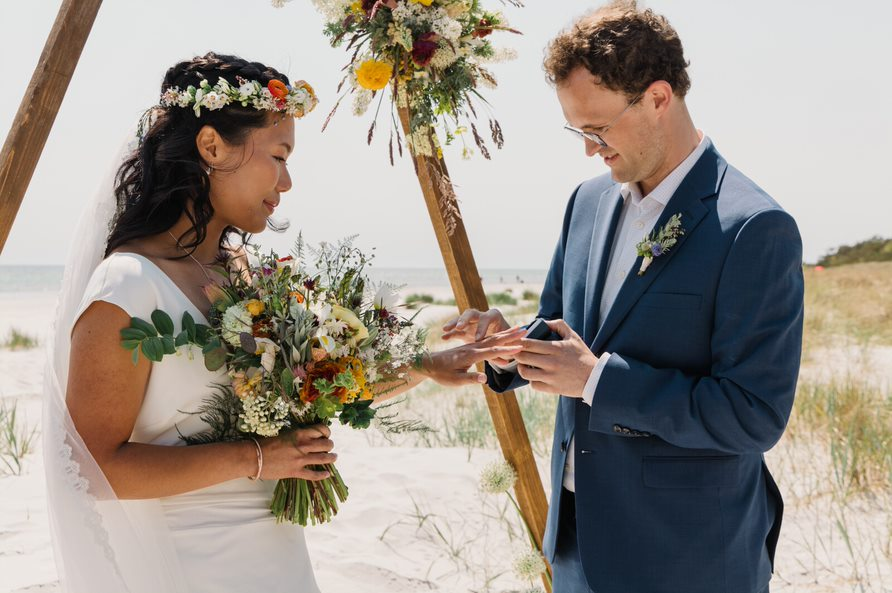 Couple exchanges wedding bands during a beach wedding on Bornholm.