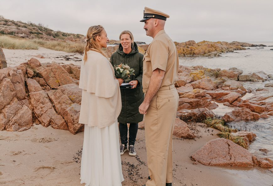 A groom in uniform with his bride during a beach wedding on Bornholm in Denmark.