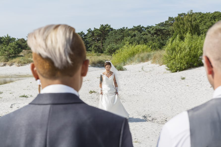 Bride walks down a natural aisle during a beach wedding on Bornholm in Denmark.