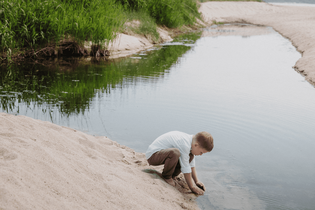 A little boy is playing in a rockpool after the beach wedding of his parents on Bornholm in Denmark.