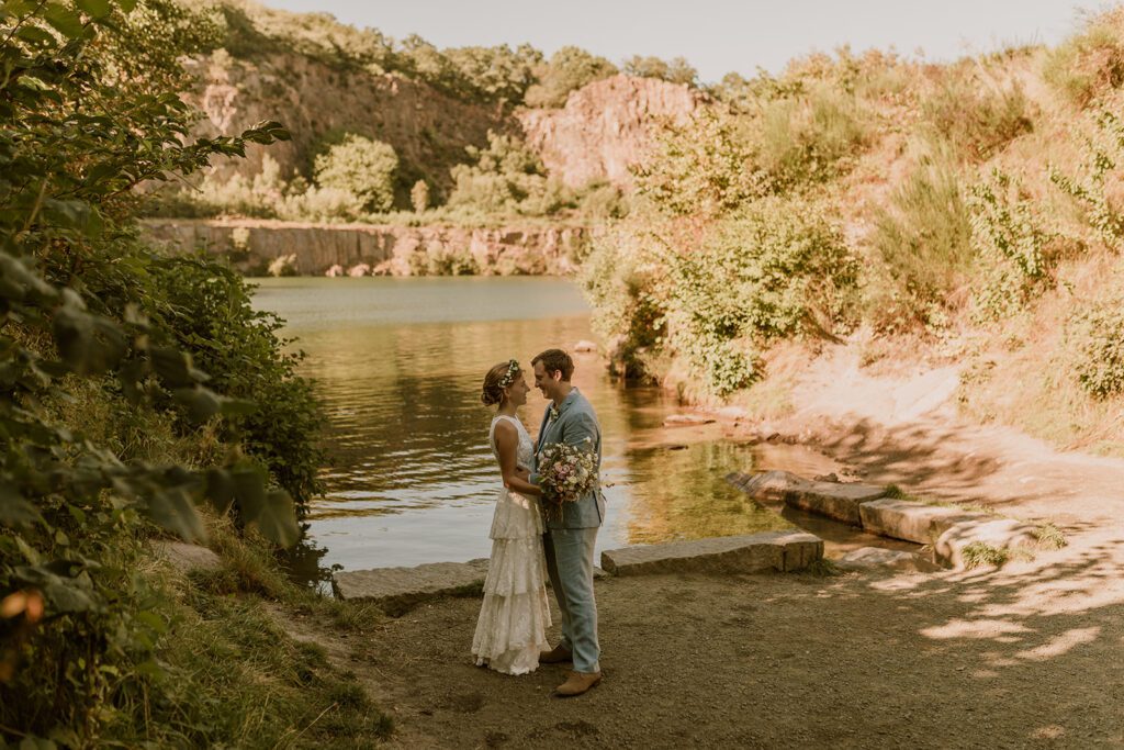 A just married couple poses at a Danish lake on Bornholm for the wedding photographer.