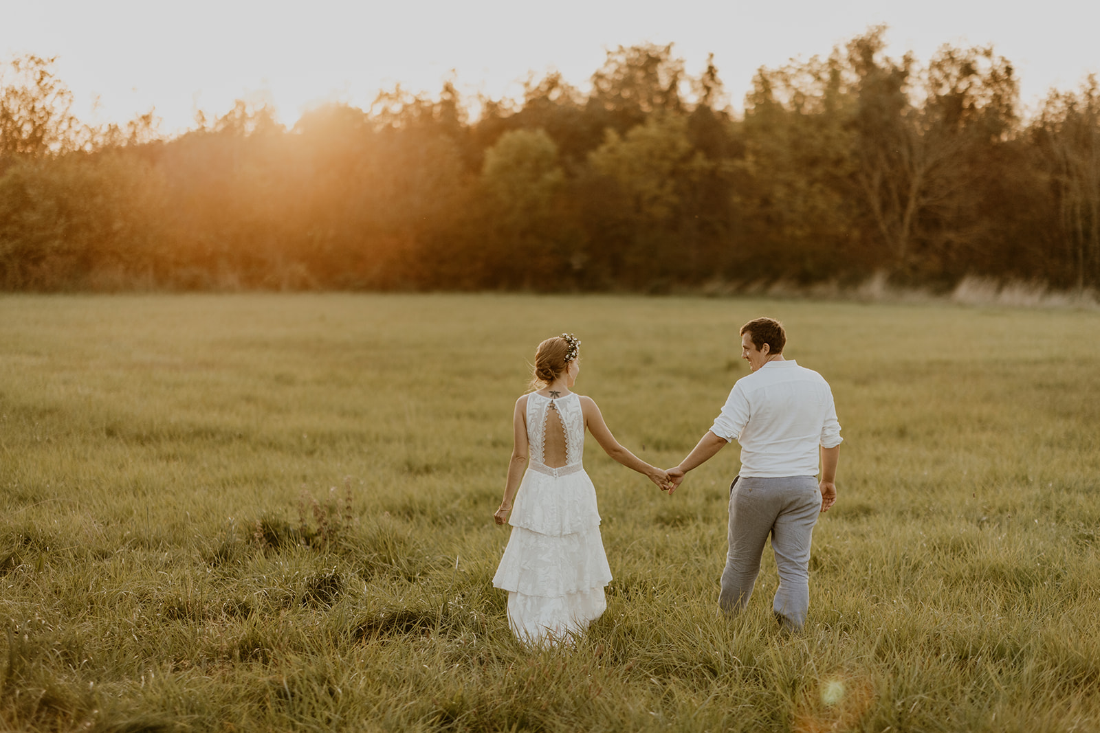 A couple on a honeymoon walks in a field on Bornholm after their wedding.