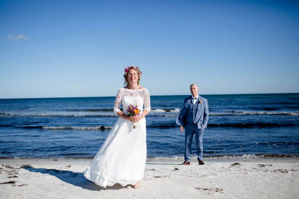 Braut und Bräutigam in ihrer perfekten Hochzeitskleidung an einem Strand auf Bornholm in Dänemark.