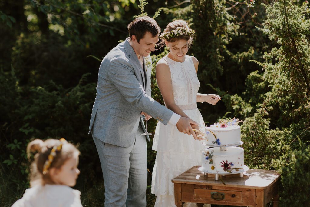 A couple cuts their wedding cake on Bornholm as their daughter looks on.
