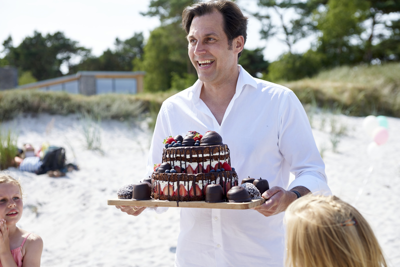 A baker arrives with a beautifully decorated wedding cake on the beach in Denmark.