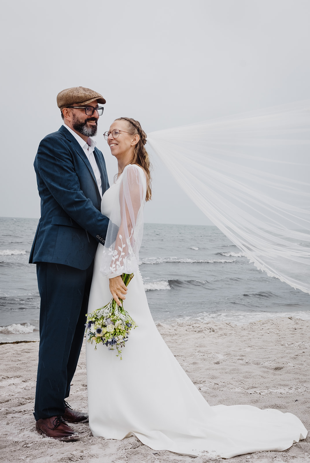 Ein Paar am Strand auf Bornholm, der Schleier weht im Wind.