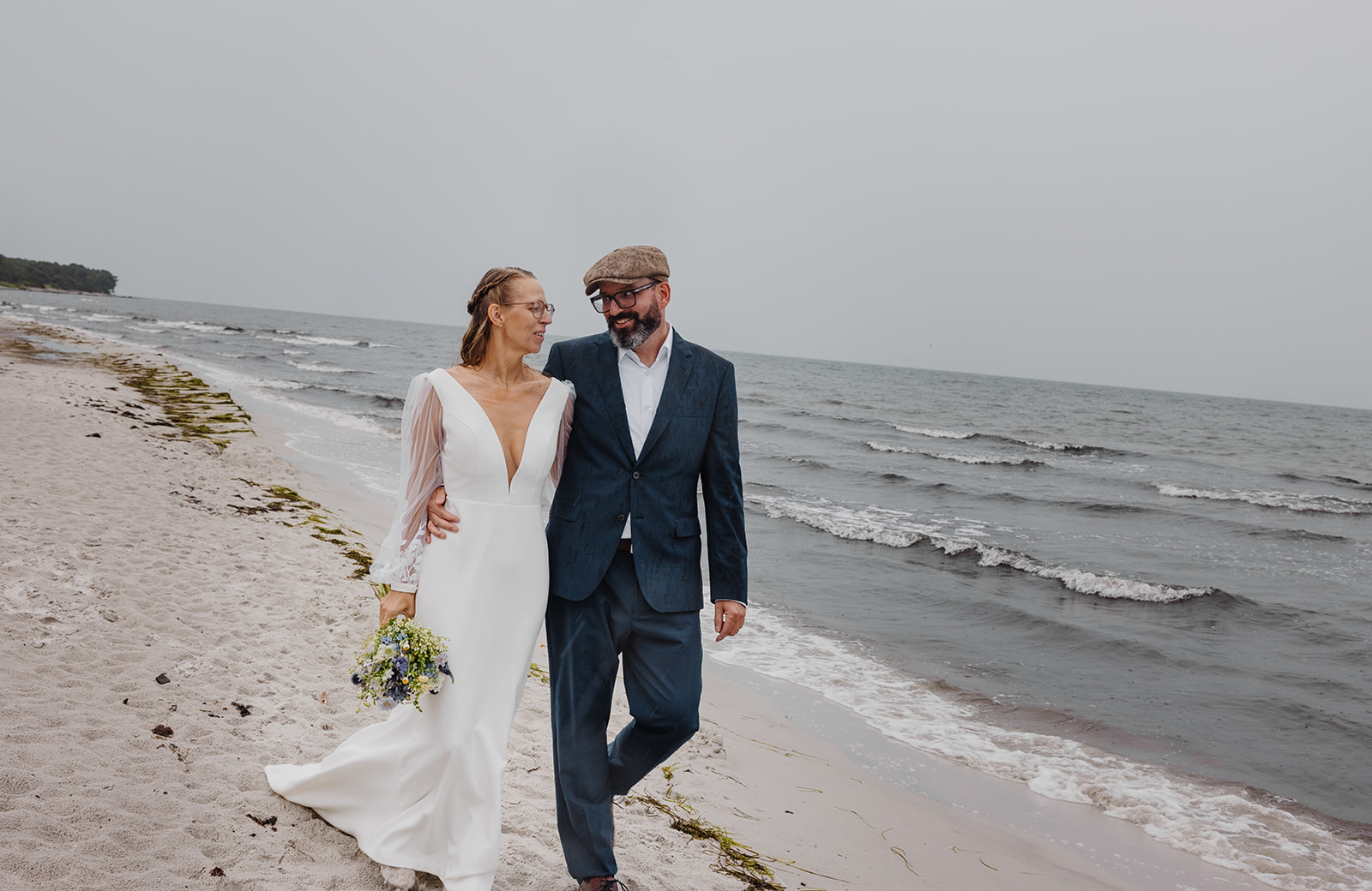 Ein Paar spaziert mit Blumenstrauß am Meer auf Bornholm.